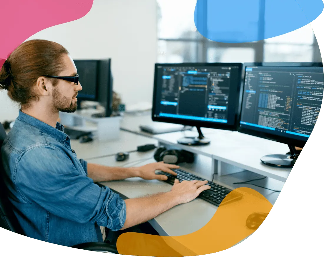Person working at a desk with two monitors showing code