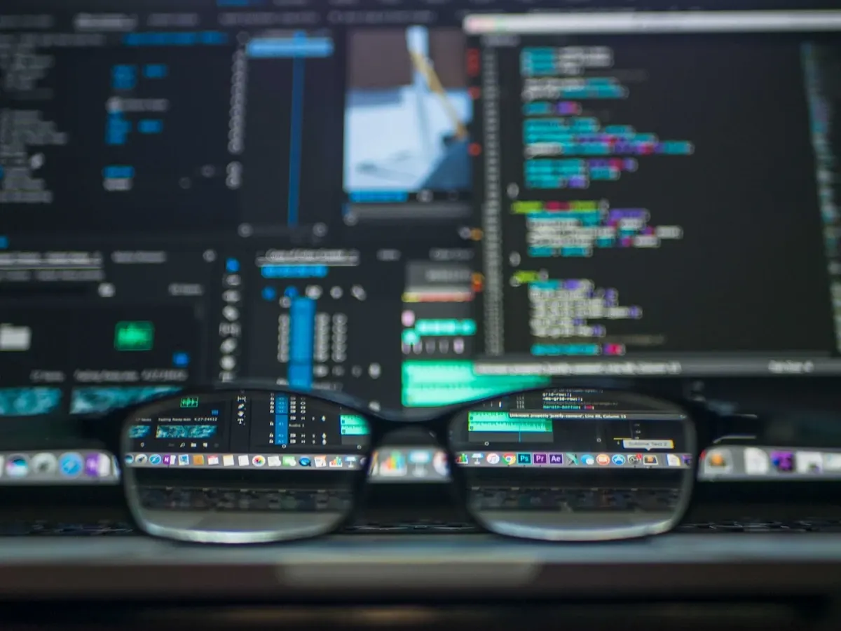 Eyeglasses in front of multiple computer screens displaying code and data analytics representing restaurant AI adoption statistics and trend analysis
