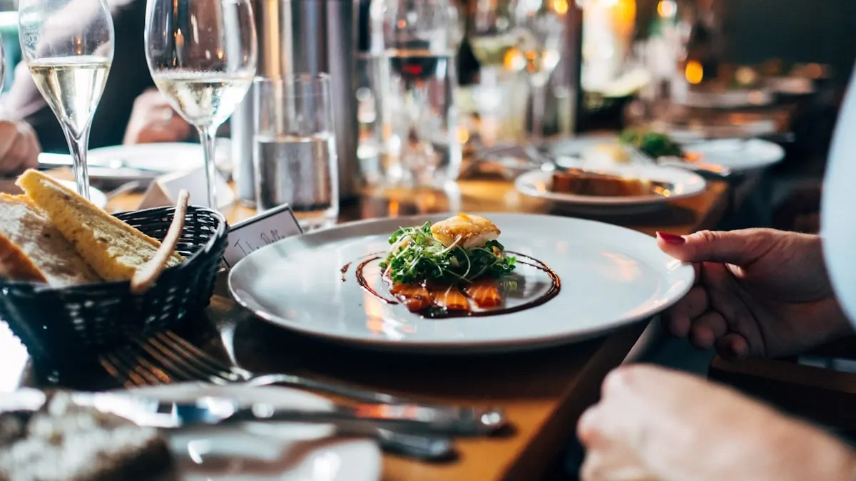 Elegant gourmet dish on white plate with wine glasses and warm ambient lighting at a fine dining restaurant table representing global culinary culture and diversity
