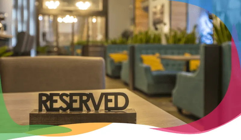 Wooden 'Reserved' sign on a restaurant table with booth seating in the background