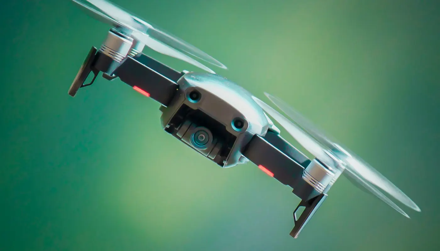 Delivery drone hovering above modern restaurant rooftop with cyan LED landing lights at twilight