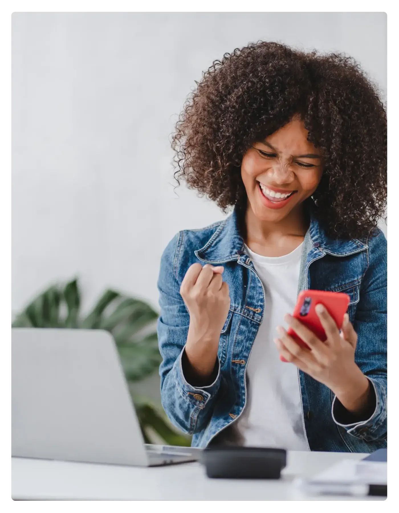 Woman celebrating while looking at her phone after receiving a gift card