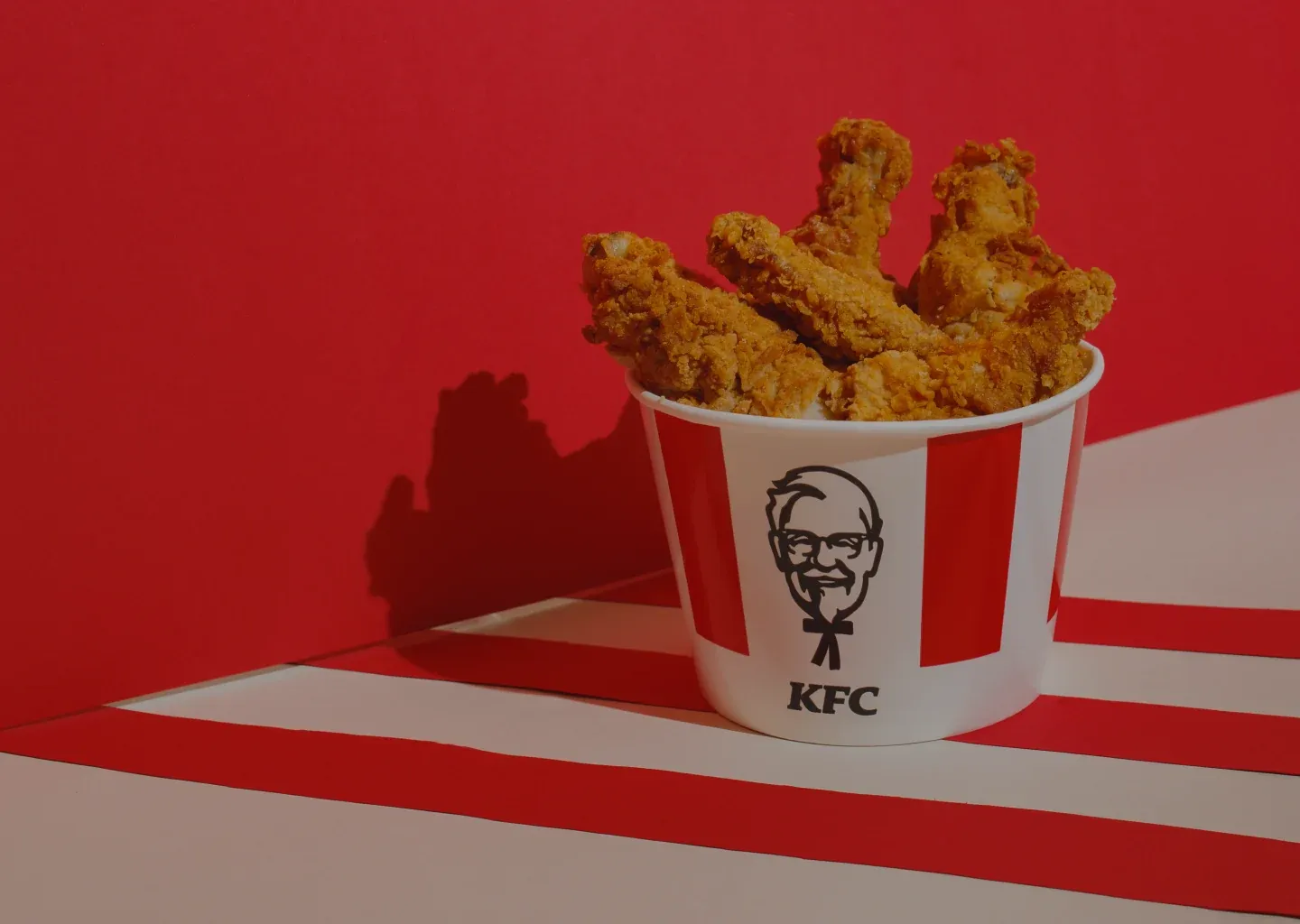 A KFC bucket of fried chicken on a red and white striped surface