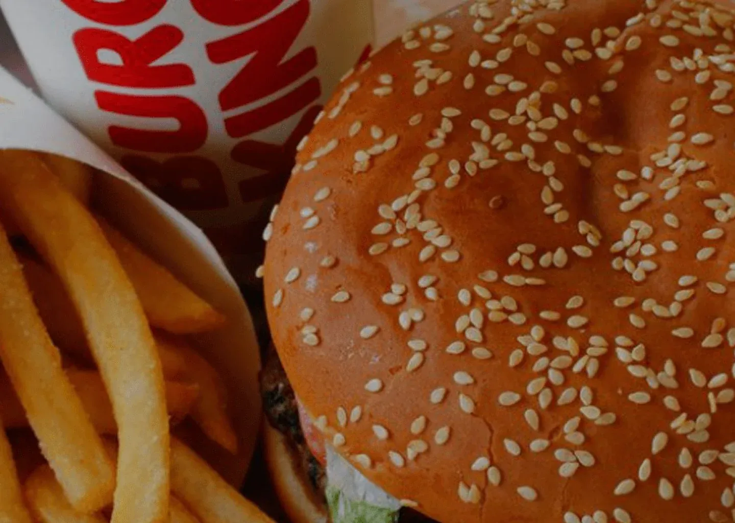 A Burger King sesame-seed burger next to fries and a Burger King cup