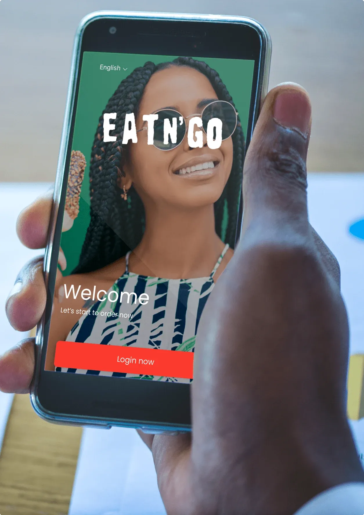 Phone showing the EatN'Go app welcome screen with a language selector and a Login now button
