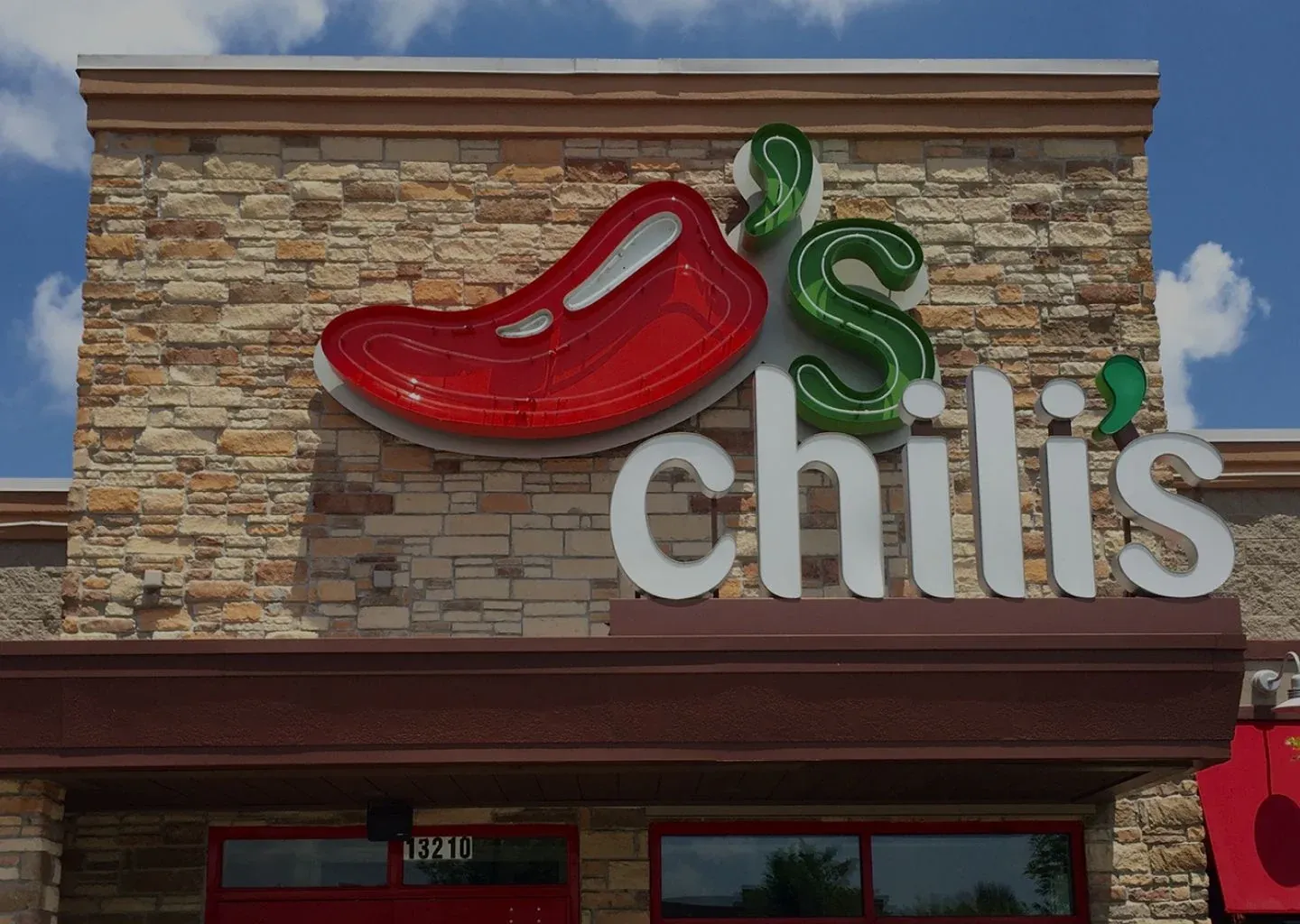 The Chili's sign with its red chili pepper on a stone restaurant facade