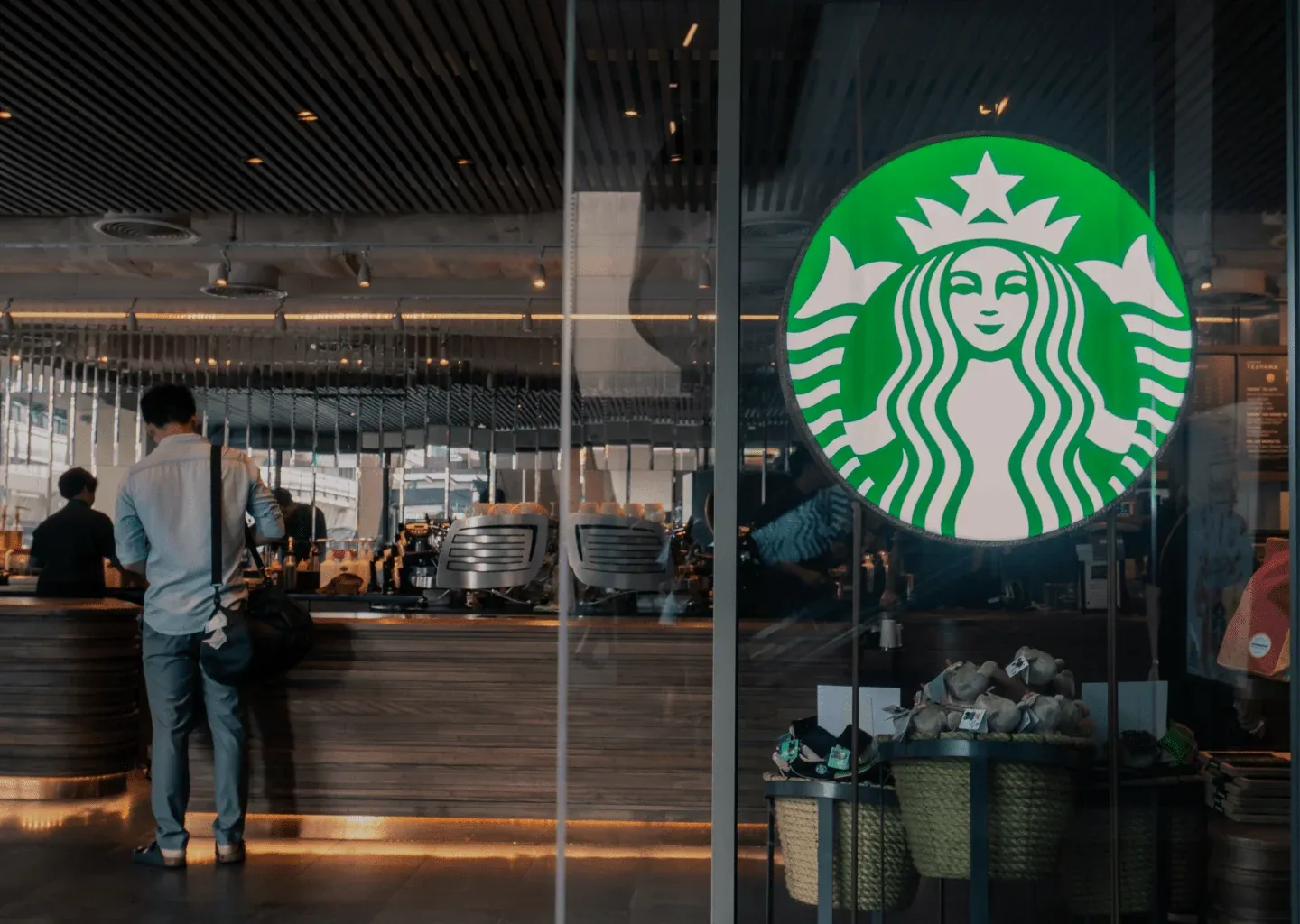 A Starbucks store seen through its glass front, with the green Siren logo on the window and the coffee bar inside