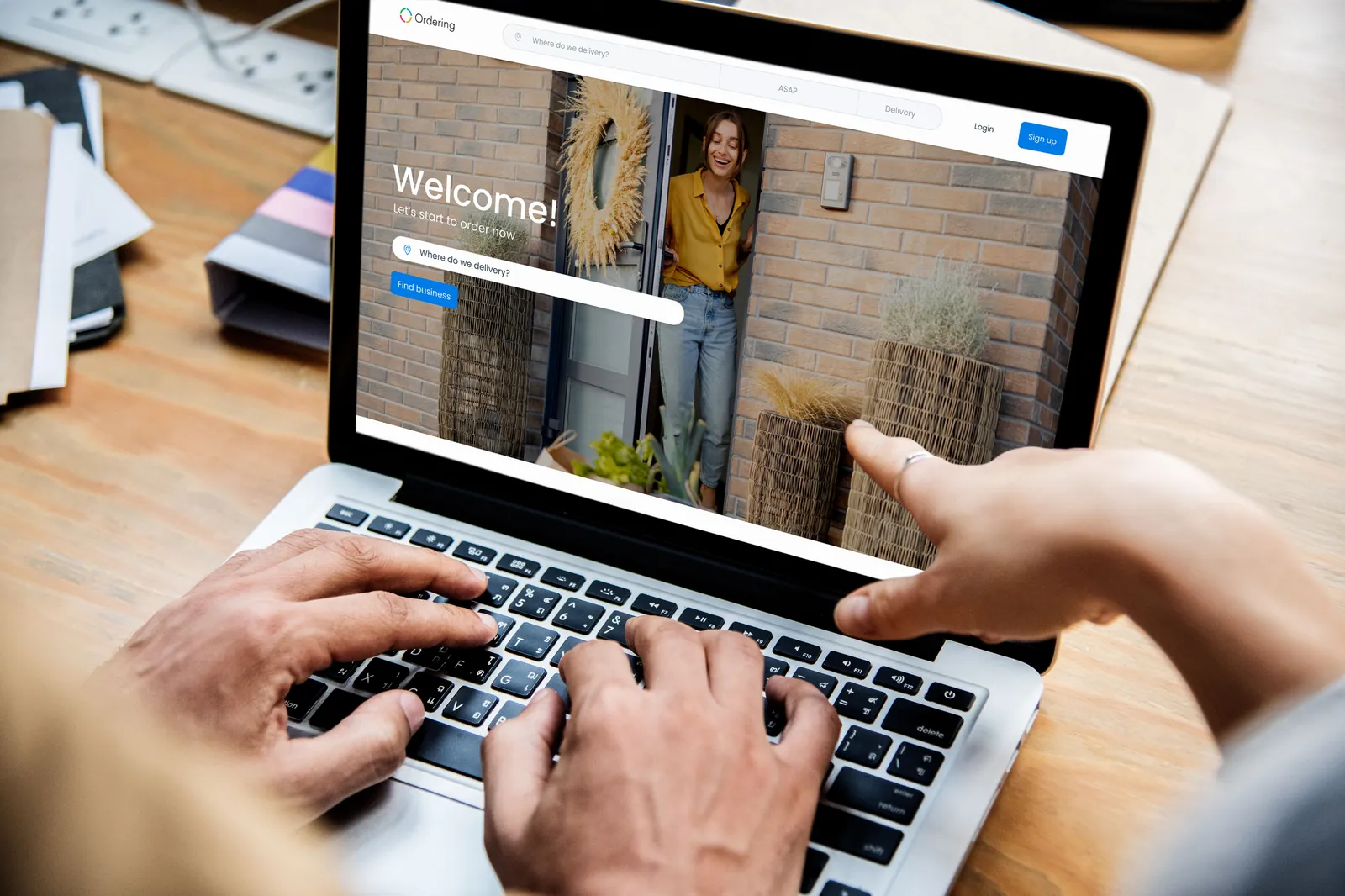 A customer opens a branded Ordering.co storefront on a tablet, showing a Welcome screen with the business’s own colors, a delivery address search bar, and Login and Sign up buttons.