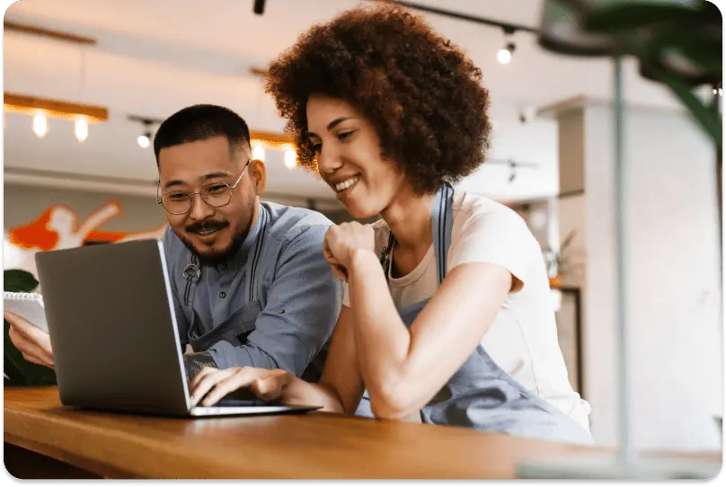 Two restaurant team members planning their online ordering setup on a laptop
